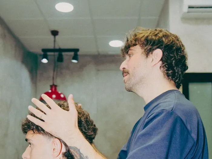 Pablo cortando bajo la lámpara roja y los focos del local